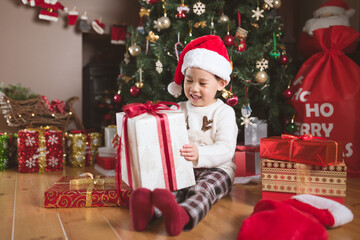 young girl sit on floor and open Christmas gift box at home