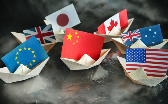 paper ship with Flags of USA, Great Britain, Canada, Australia, Japan,EU and China concept of conflict, shipment or free trade agreement
