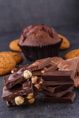 Chocolate cupcake with icing and chocolate bar in Dark lighting,Homemade delicious chocolate muffin on wooden background close-up