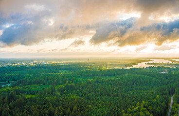 aerial view of green forests, lakes and a high-voltage transmission line under a cloudy sky