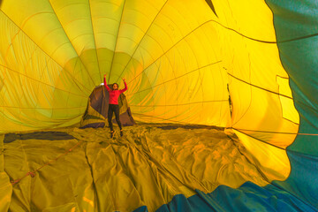 happy jumping girl inside of being inflating yellow air balloon