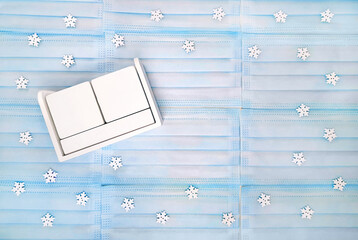 Winter flat lay with blue medical mask and white wooden block calendar. Blank frames for date and month. Snowflakes on background.