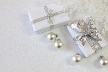 Bożonarodzeniowa srebrno-biała dekoracja z prezentami, bombkami i oszronionymi gałązkami  © Monika
