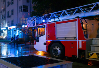 Fire engines in the courtyard of the apartment building where the fire occurred, at night during the rain.
