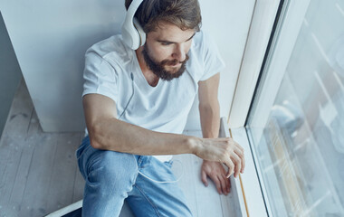 bearded man in headphones music rest interior near window