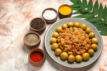 bottom view roasted eggplant salad on plate different spices in small bowls on nude background