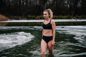 Fototapeta premium Young slender girl bathes in winter in a river hole