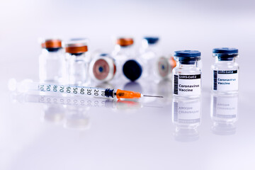 New vials of coronavirus vaccine to cure Covid-19 with a syringe, isolated on white laboratory background.