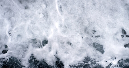Froth and foam on dark turbulent water, panoramic frame.