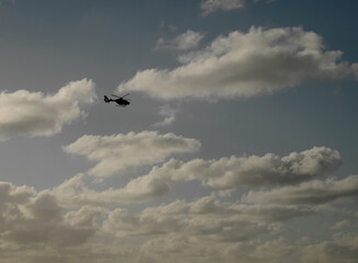 Helicopter in vast open sky. Silhouette, low key, large copy space.