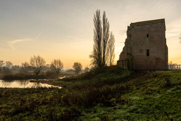 Fototapeta na wymiar Silhouette of ruins of Nijenbeek castle in The Netherlands along the river IJssel in a swampland landscape at sunrise