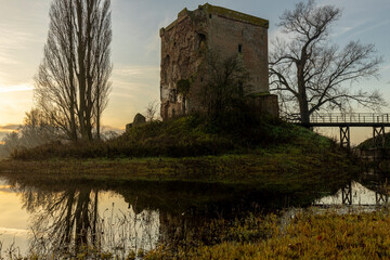 Closeup view of the remaining ruins of Nijenbeek castle in The Netherlands along the river IJssel at sunrise reflecting in the still swamp water in front
