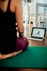 Woman practicing yoga at home with video tutorial.