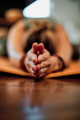 Woman lying down in child yoga position. Selective focus on hands.