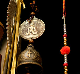 Buddha medal, charm wheel, bell and beads - symbols and signs of indian (hindu) and buddhist religions and tradition, low angle close view. - obrazy, fototapety, plakaty
