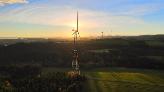 Drone shot of wind turbine at sunrise with sun behind the blades