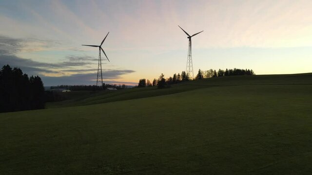 Drone shot panning up of wind two wind turbines at sunrise