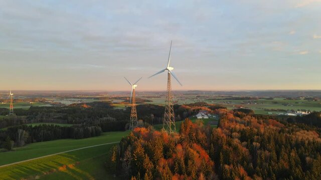 Drone shot panning right on two wind turbines at sunrise