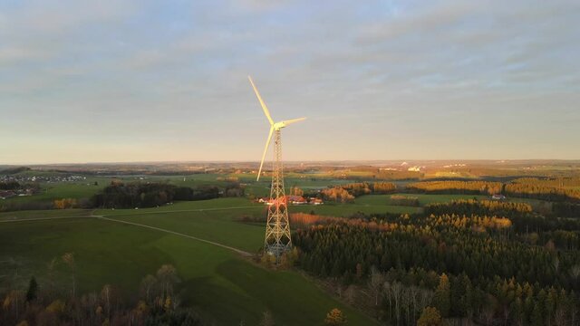Drone shot rotating wind turbine at sunrise