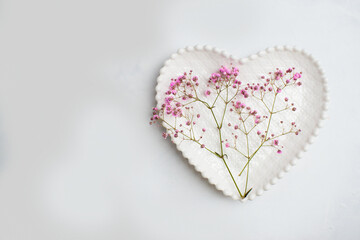 Top view romantic table setting for valentine's day. The celebration of the wedding date. Pink flowers on a plate in the shape of a heart. romantic background.