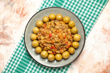 top view roasted eggplant salad and pickled plums on plate on turquoise white checkered tablecloth on nude background