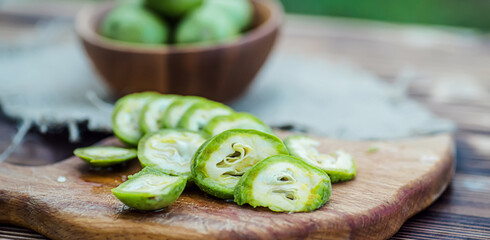 healthy food. Walnuts, cut into slices, are scattered on a cutting board. Old vintage table and whole unripe walnut fruit