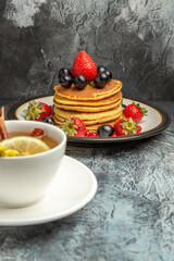 front view cup of tea with pancakes and fruits on a dark floor morning breakfast food