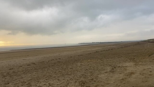 sunset beach storm beach camber sands in East Sussex, UK sand dunes pan to sunset low tide flat sandy beach 
