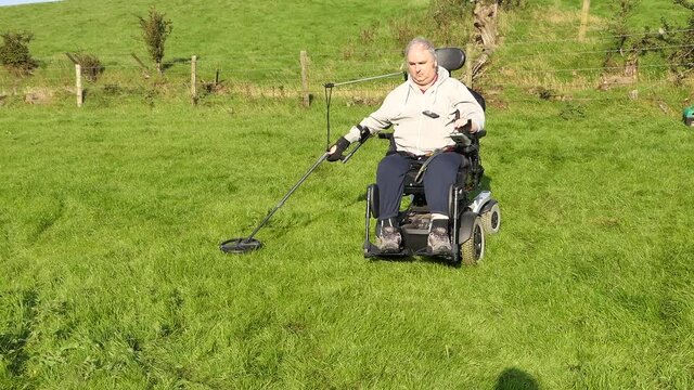Disabled Wheelchair user metal detecting in a field