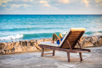 Person from the back laying on lounge beach chair looking at the ocean