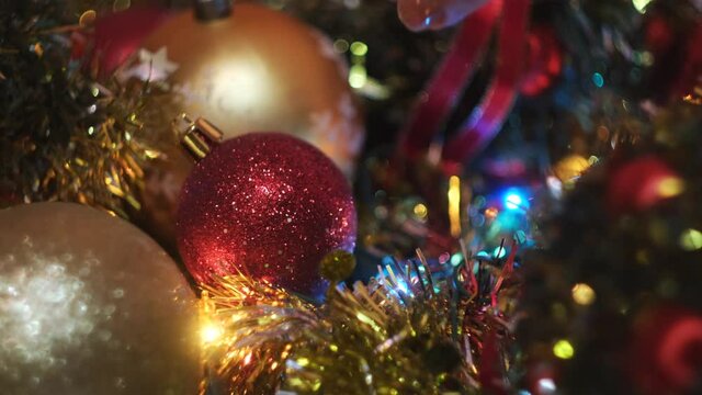 Most beautiful Christmas tree decorations for winter hollidays. Concept. Close up of woman hand putting red ball toy to the other toys and shining garland.