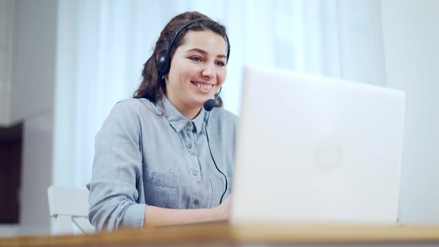 Close up young woman wear headset communicating by conference call speak looking at computer at home office video chat job interview or distance language course class with online teacher Female laptop