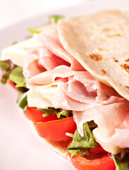 Traditional Italian piadina with ham, cheese, tomato and salad.