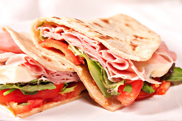 Traditional Italian piadina with ham, cheese, tomato and salad.