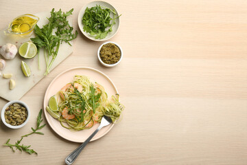Tasty zucchini pasta with shrimps and arugula served on wooden table, flat lay. Space for text