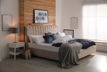 Comfortable bed with pillows and soft blanket in room. Stylish interior design