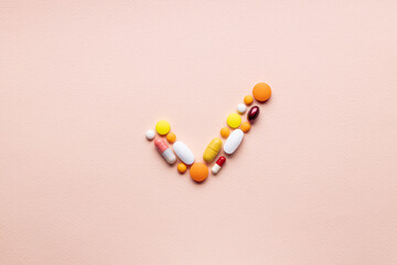 medical pills check mark symbol isolated on pink background. medicine approve sign concept. outer space. above view