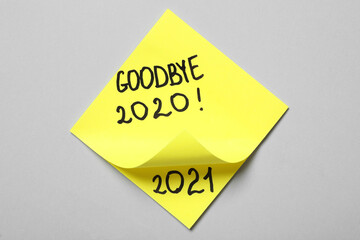 Yellow memory stickers with text Goodbye 2020 and number 2021 on light grey background, top view