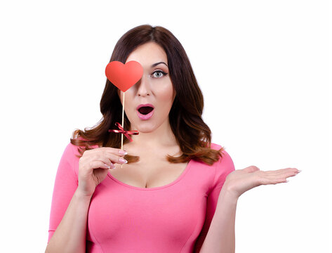 On Valentine&rsquo;s day, A pretty Caucasian girl is holding a red paper heart in front of her eye.  isolated. white background.
