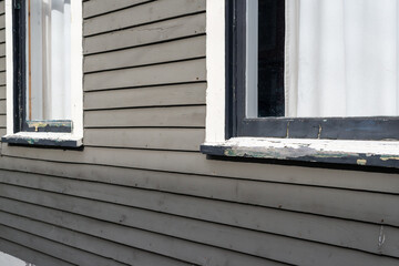 The exterior charcoal grey wooden horizontal clapboard siding of a wood building. There are two...