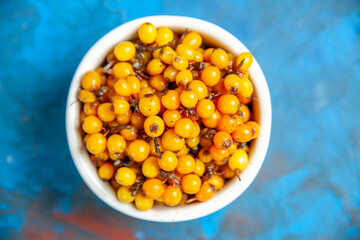 top view sea buckthorn in bowl on blue background