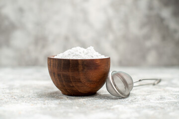 front view a bowl of powered sugar and a sieve on grey isolated background with copy space