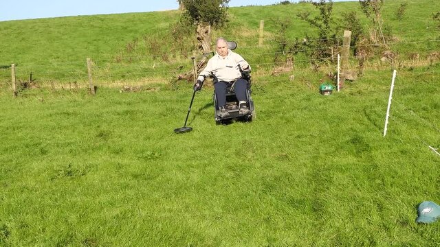 Disabled Wheelchair user metal detecting in a field