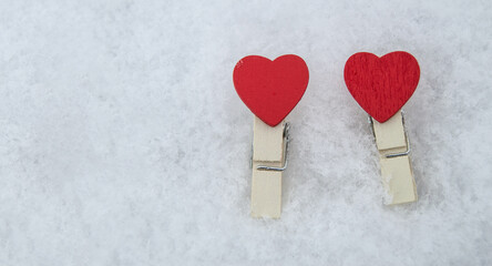 Decorative wooden clothespins in the form of two red hearts lie on the snow, the Concept of love and Valentine's Day