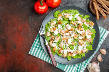 top view caesar salad on oval plate green white checkered tablecloth garlic tomatoes on dark red background free place