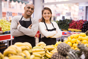 Portrait of positive man and woman salesmen at grocery supermarket