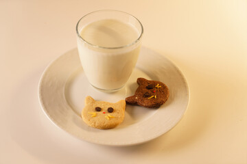 Cocoa and gingerbread cookies for New Year's Eve and Christmas themed. An image of a cat-like cookie and a glass of milk with a Christmas tree and fireplace in the background.