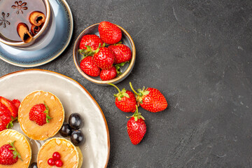 top view little yummy pancakes with fruits and cup of tea on a grey background pie cake fruit