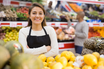 Spanish woman employee in fruit store with green melons