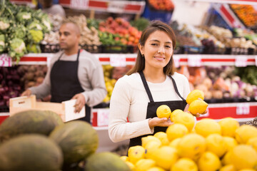 Merchandiser lays out ripe lemons on the shelves in the supermarket